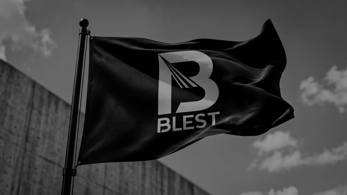 Black Blest flag with the white Blest logo flying outdoors against a cloudy sky